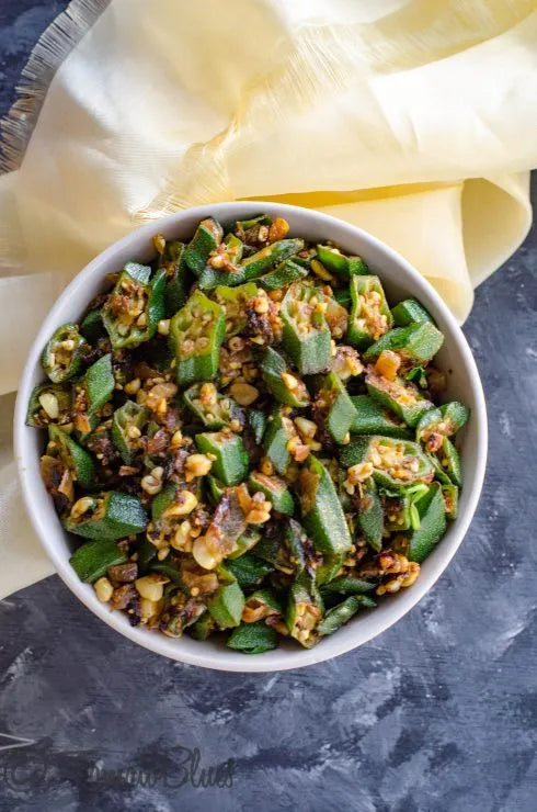 White bowl filled with okra dish on a dark surface with a yellow cloth